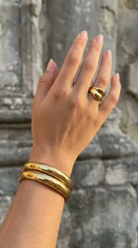 Main portant une bague et deux joncs dorés